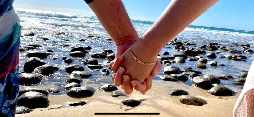 Two hands held over a rocky shore